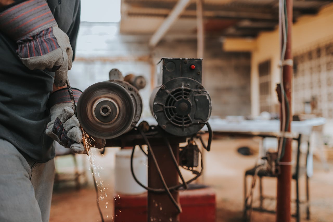 A worker skillfully operates a grinder in a workshop, emitting sparks.